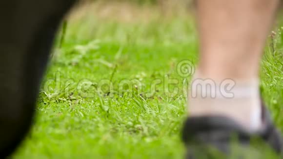 一个穿运动鞋的人穿过绿草人的双腿合拢视频的预览图