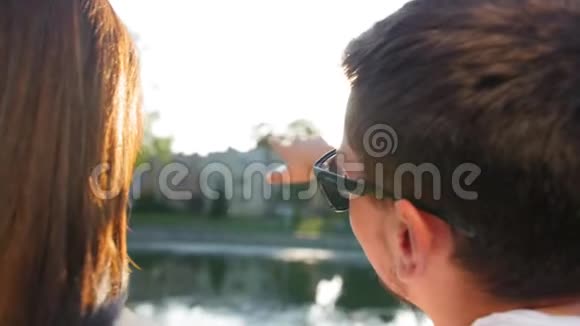 浪漫的一对夫妇在日落时坐在池塘附近的绿草上后景夫妻信任爱情和视频的预览图