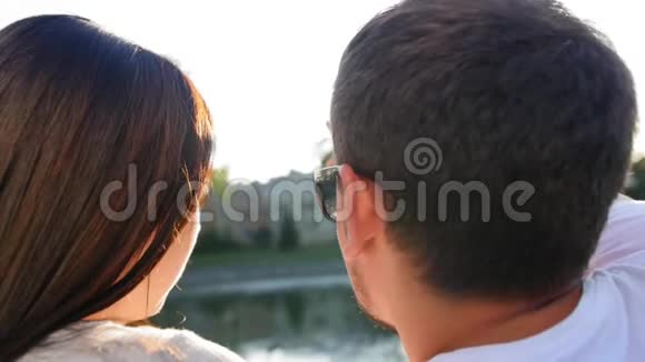 浪漫的一对夫妇在日落时坐在池塘附近的绿草上后景夫妻信任爱情和视频的预览图