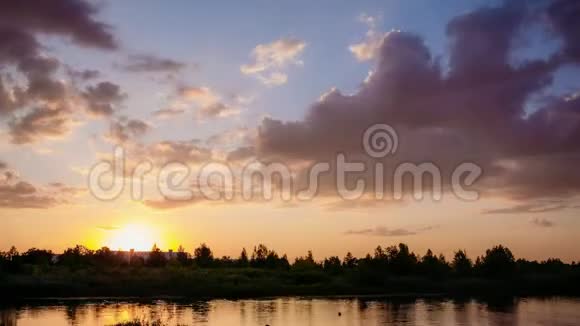 太阳在地平线上落下森林在河的上方夏季视频的预览图