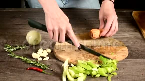女厨师将切好的胡萝卜切在切好的蔬菜旁边的木切割板上的概念视频的预览图