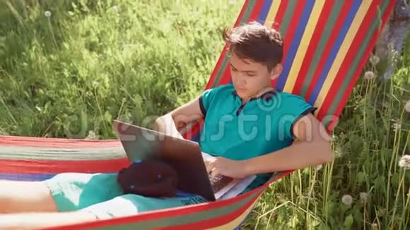 一个躺在吊床上用笔记本电脑工作的年轻人视频的预览图