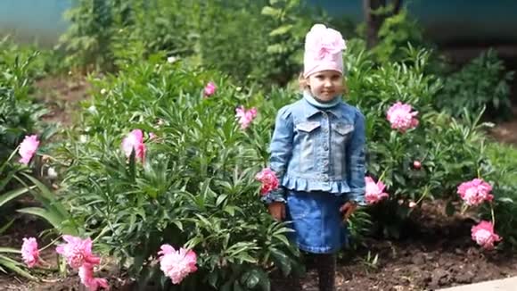 小女孩送空气吻花园里有牡丹和有趣的婴儿视频的预览图