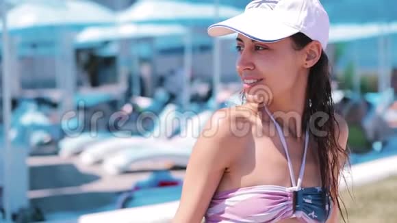 美丽苗条的年轻女子比基尼和白色棒球帽在海岸与蓝天水疗酒店快乐的女人视频的预览图