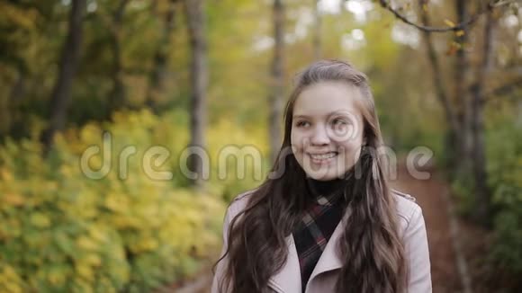 特写美丽少女的画像戴牙套的女孩在秋天公园的镜头前微笑视频的预览图