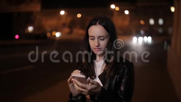 午夜美丽的女孩使用智能手机午夜女孩站在街道上靠近道路使用智能手机视频的预览图
