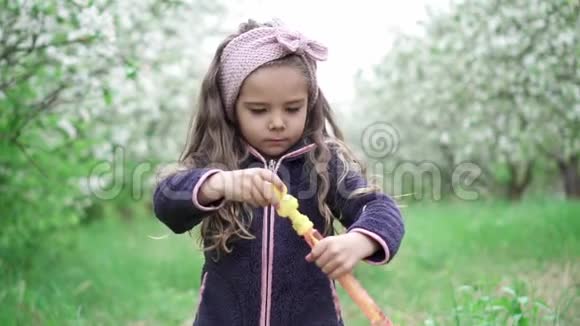 小女孩在盛开的花园里玩肥皂泡慢动作视频的预览图