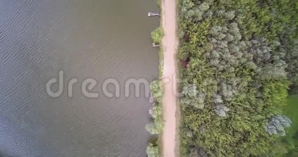 用渔人桥和泥土碎石路森林俯瞰乡村湖景视频的预览图
