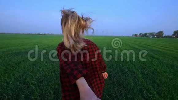 跟着我年轻快乐的女孩在日落时分穿过一片绿色的小麦地慢动作镜头耀斑视频的预览图