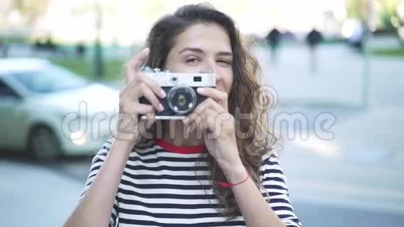 微笑着年轻的摄影师女士在夏天用老式相机拍摄视频的预览图