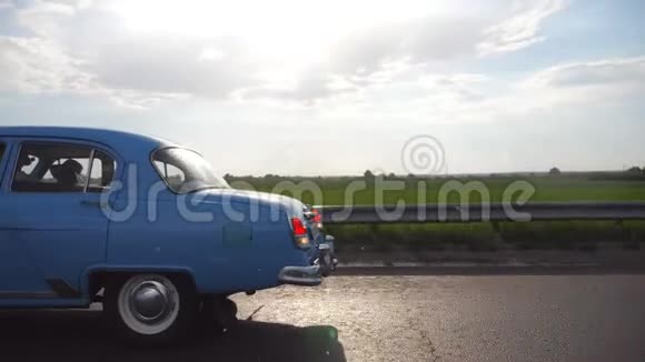 夏季雨天在高速公路上行驶的经典老车年轻夫妇开着老式汽车在乡间小路上视频的预览图