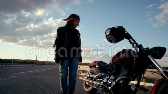 一个穿着皮夹克和手套的老自行车手来到一条空路的背景上坐在上面这就是视频的预览图