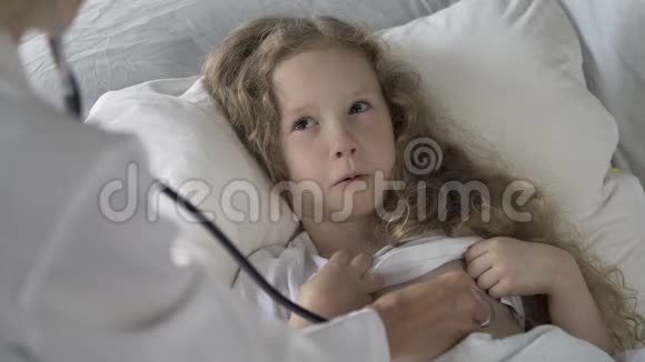 生病的孩子躺在床上哭着医生用听诊器检查她视频的预览图
