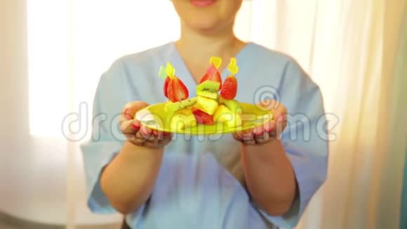 那个女人厨师微笑着拿着一个盘子手里拿着一份水果甜点控制来自窗户的阳光中间计划视频的预览图