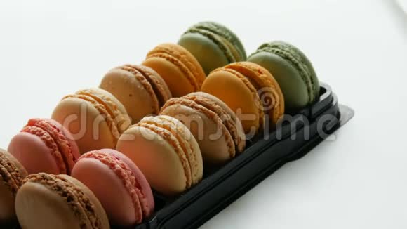 五颜六色的法国饼干通心粉在一个特殊的黑色盒子上的白色桌子礼品盒中的彩色蛋糕苹果视频的预览图