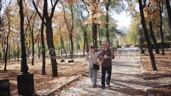 一对老夫妇在秋天公园散步一位老人在秋公园散步喝着咖啡视频的预览图