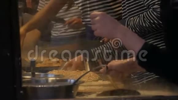 厨师手在快餐店准备煎蛋卷煎饼面条等美味菜肴妇女和男子的侧视视频的预览图