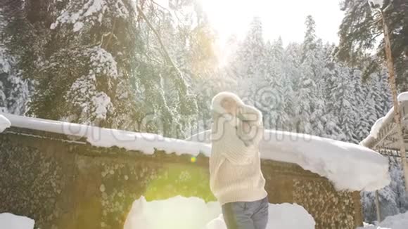 快乐的女人享受阳光明媚的冬天早晨在雪地里旋转在阳光下闪闪发光的雪花视频的预览图