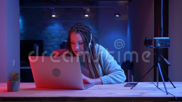 年轻有魅力的女性博客写手用笔记本电脑在摄像头上说话耳机里有可怕的恐惧症视频的预览图