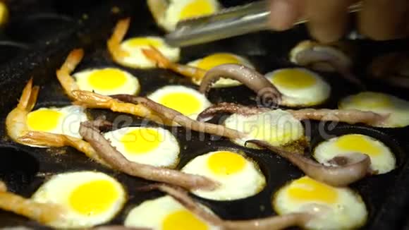 街头小贩用鱿鱼触角和对虾准备煎鹌鹑蛋视频的预览图