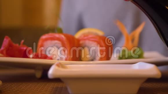 在亚洲餐厅为新鲜日本寿司卷浇酱油视频的预览图