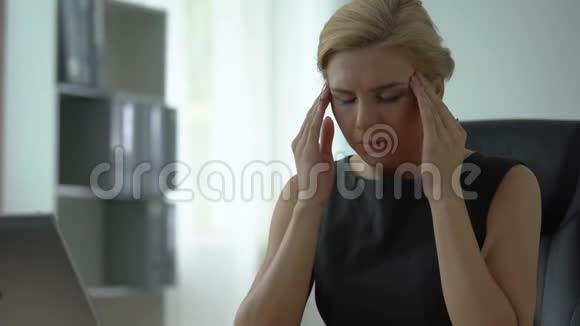 疲惫的女老板坐在办公桌旁头痛紧张视频的预览图