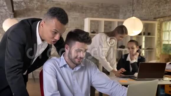 两位年轻的商人正在办公室里观看笔记本电脑与技术建立联系讨论背景工作视频的预览图
