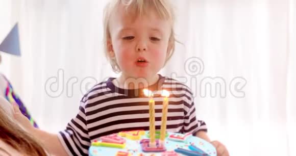 可爱的男孩在蛋糕上吹了两支蜡烛生日视频的预览图