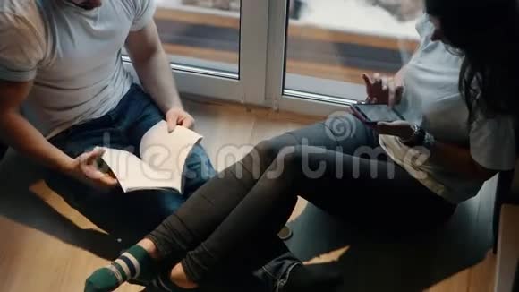 一对男女在房子的窗户旁的楼梯上阅读和讨论这本书视频的预览图