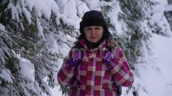 白雪皑皑的树林里的年轻女子年轻漂亮的游客独自站在森林里看着镜头她很冷静视频的预览图