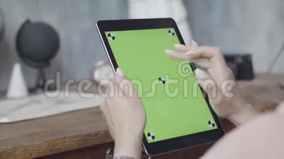 女性手持平板电脑的侧面视图木制桌子背景上有绿色屏幕库存录像把一个女孩关起来视频的预览图