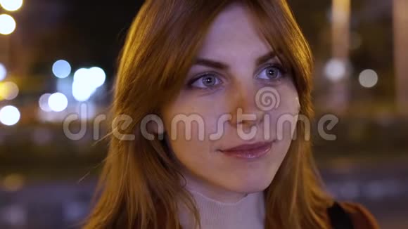 一个年轻的红发迷人的女人在户外夜晚的特写广告招牌上的闪光灯视频的预览图