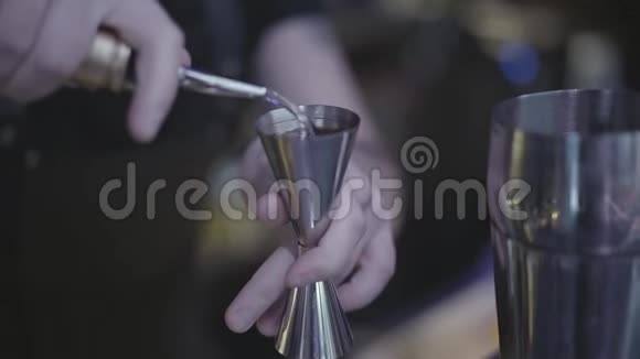 将调酒师手中的饮料从量杯中倒入一个金属摇床视频的预览图