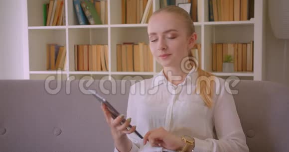 年轻漂亮的白种人金发女学生使用平板电脑的特写肖像并显示绿色的彩色屏幕视频的预览图
