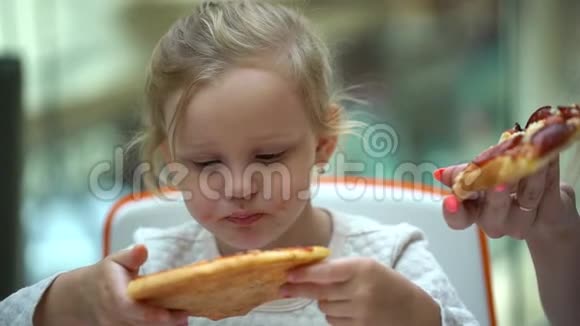 一个小孩子在快餐店吃披萨可爱的小女孩肖像有趣的吃快餐场在商场视频的预览图