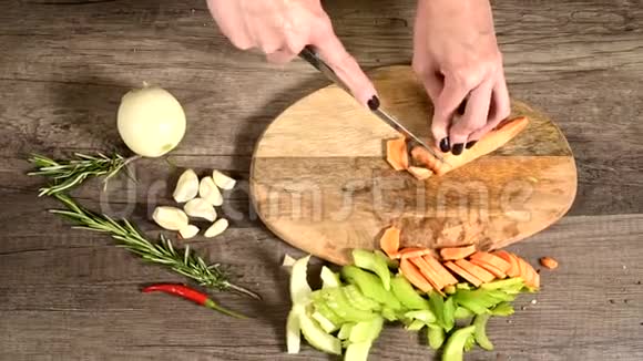 女厨师将切好的胡萝卜切在切好的蔬菜旁边的木切割板上的概念视频的预览图