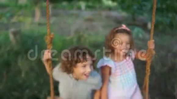 漂亮的卷发孩子在秋千上嬉戏友好的家庭暑假孩子们一天视频的预览图