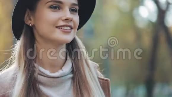 迷人的女孩一副浪漫的样子戴着黑帽子走在公园的小巷里环顾四周露出惊人的微笑视频的预览图
