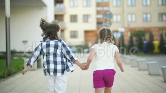 两个快乐的孩子手拉手一起跑他们的金发在风中飘扬视频的预览图