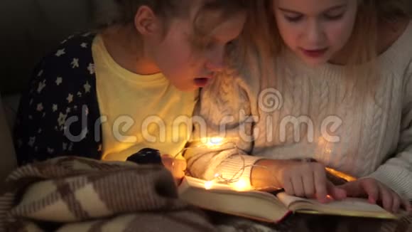 晚上两个女朋友在床上用一个小电花环看书视频的预览图