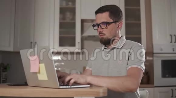 一个疲惫的男人正在电脑上打字坐在家里拿出眼镜视频的预览图