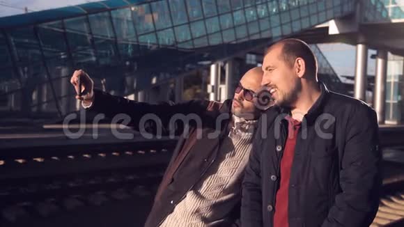 火车站站台上两个男人在等火车的到来在一张自拍上拍照视频的预览图