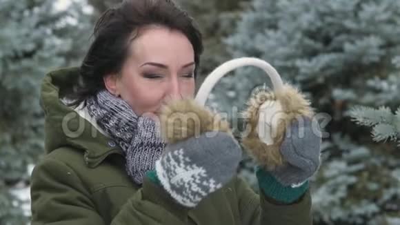 冬天森林里穿着毛皮手套的女人把手举起来美丽的风景雪杉树视频的预览图