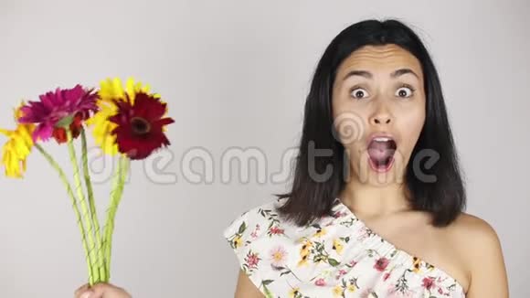 女孩脸上贴着一束花一个年轻漂亮的女人嗅着灰色花束的肖像视频的预览图