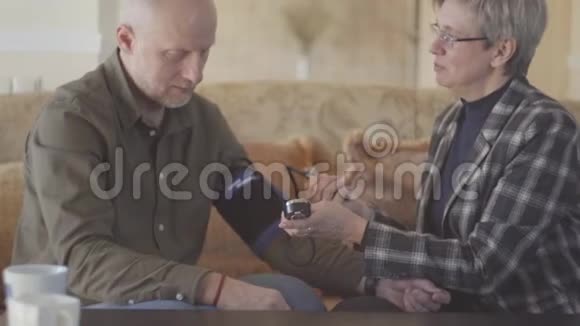 一位老妇人向她成熟的丈夫测量压力成熟的夫妻在一起妻子关心视频的预览图