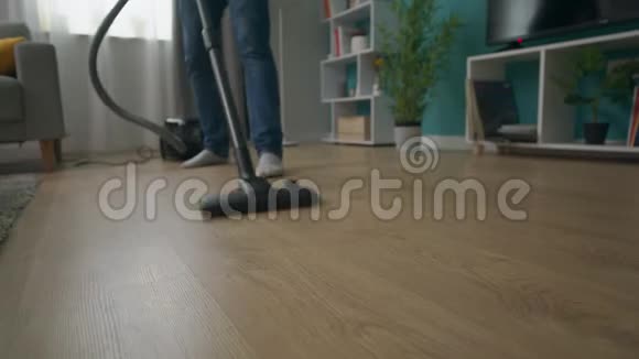 男士用吸尘器清洁舒适公寓的特写镜头视频的预览图