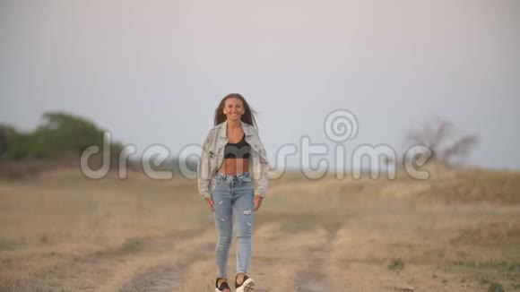穿牛仔裤的女孩在大自然中行走视频的预览图