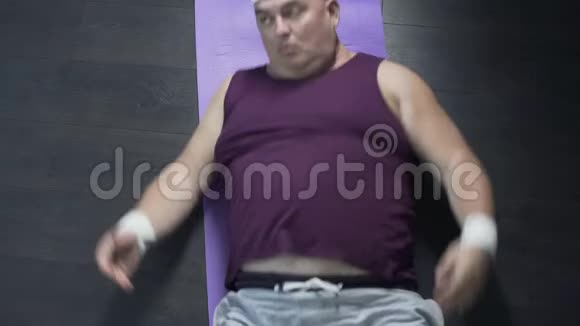 疲惫的胖子在有氧运动后在运动垫上放松的俯视图视频的预览图