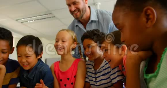 成人白种人男性教师在4k教室用笔记本电脑教孩子视频的预览图