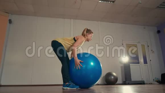 年轻的体育女士在训练场用手中的健身球独自锻炼视频的预览图